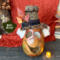 A monster pumpkin character made from a real, dried gourd. The monster is green with a big grin and top hat. He has white ghostly hair.